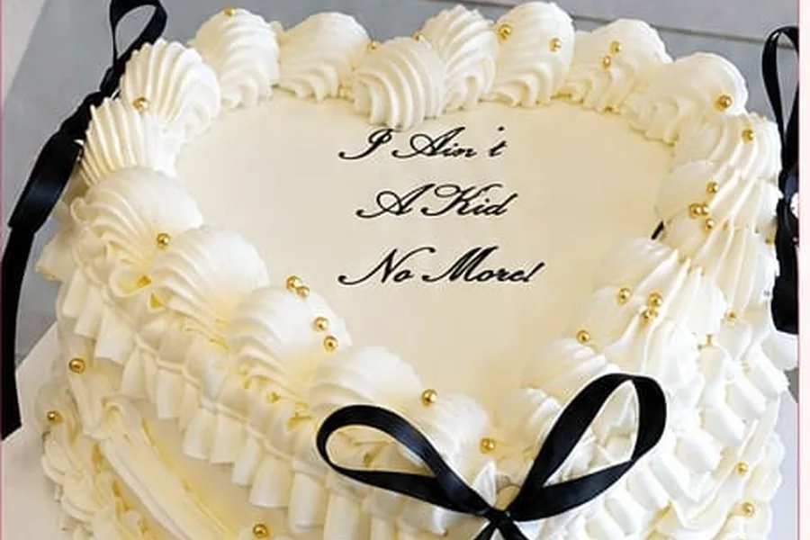 An ivory heart-shaped cake finished with piped ruffles and gold pearls