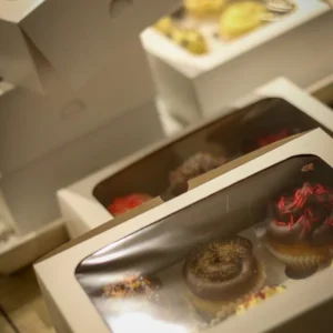White cake boxes with clear window lids, holding decorated cupcakes