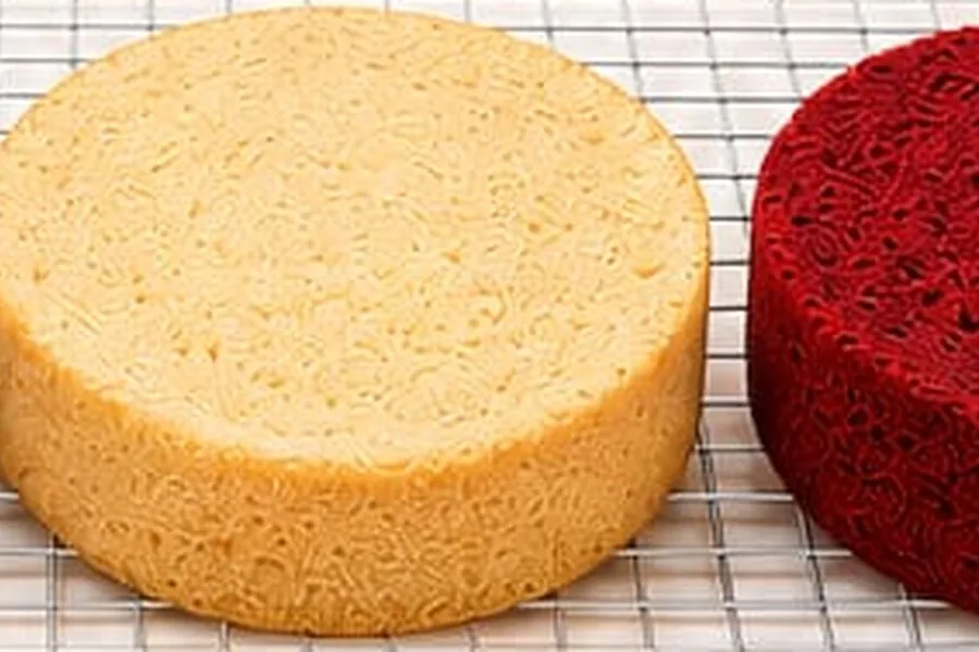 Three baked sponges, chocolate, vanilla and red velvet, cooling on a wire rack