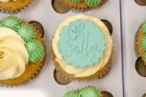 Cupcakes piped in cream and green buttercream with an Oh Baby fondant topper
